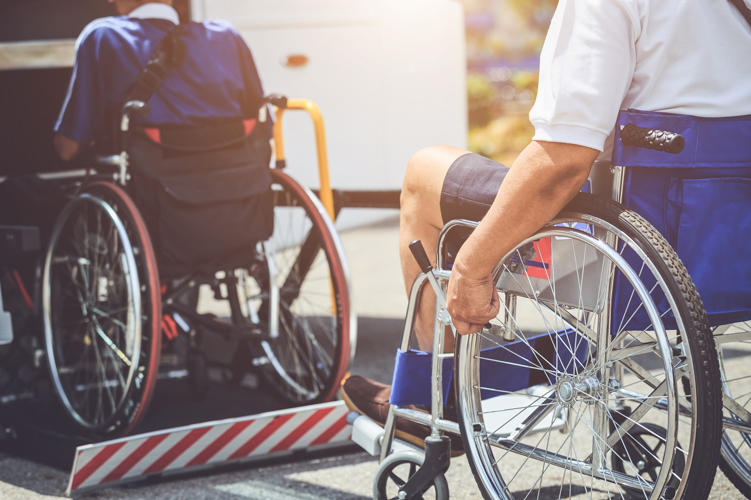 Travelers in wheelchairs boarding a bus with a lift, highlighting ADA-compliant accessible travel services.