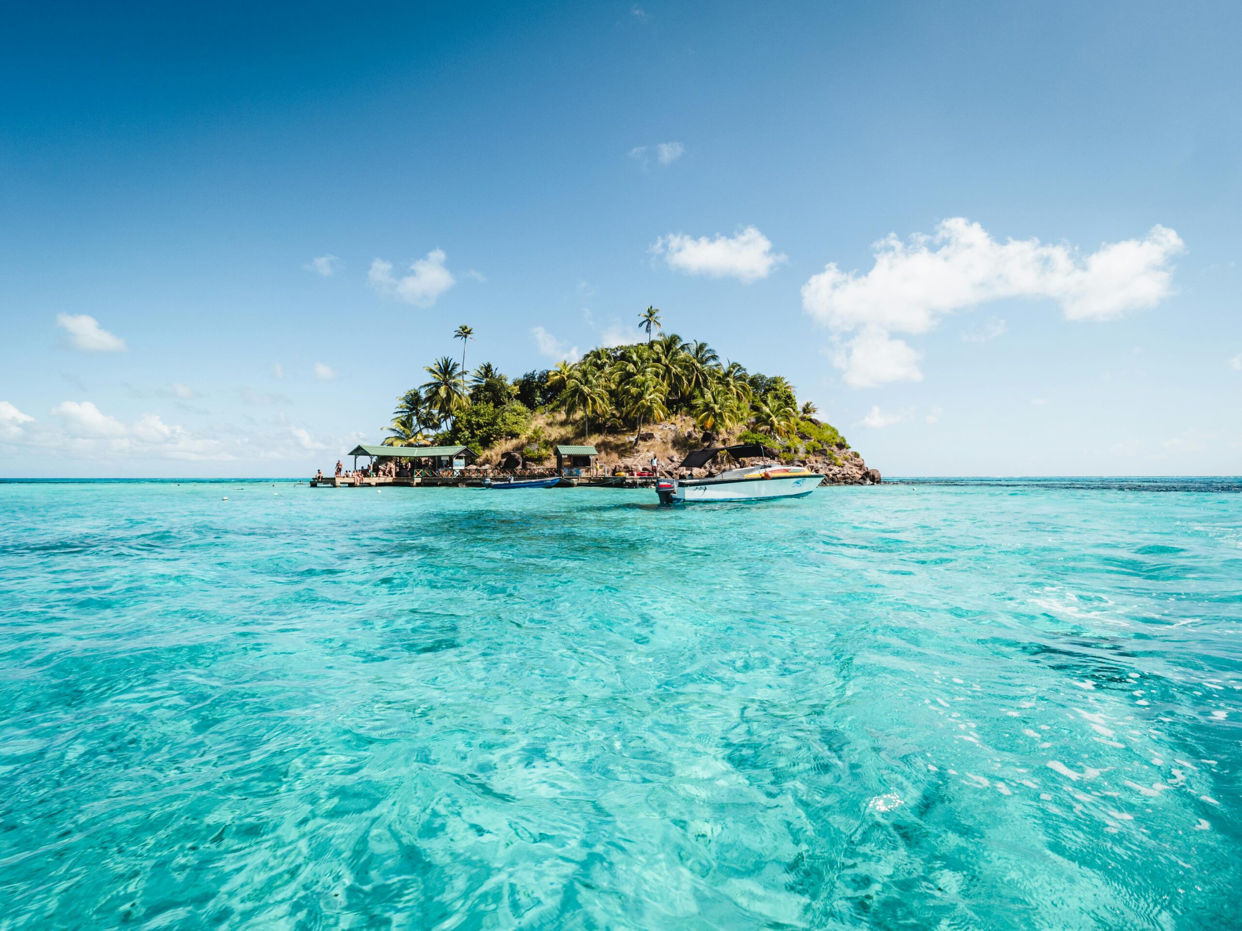 Small Fiji island viewed from water level with a canoe reflection, representing South Pacific island hopping tours.